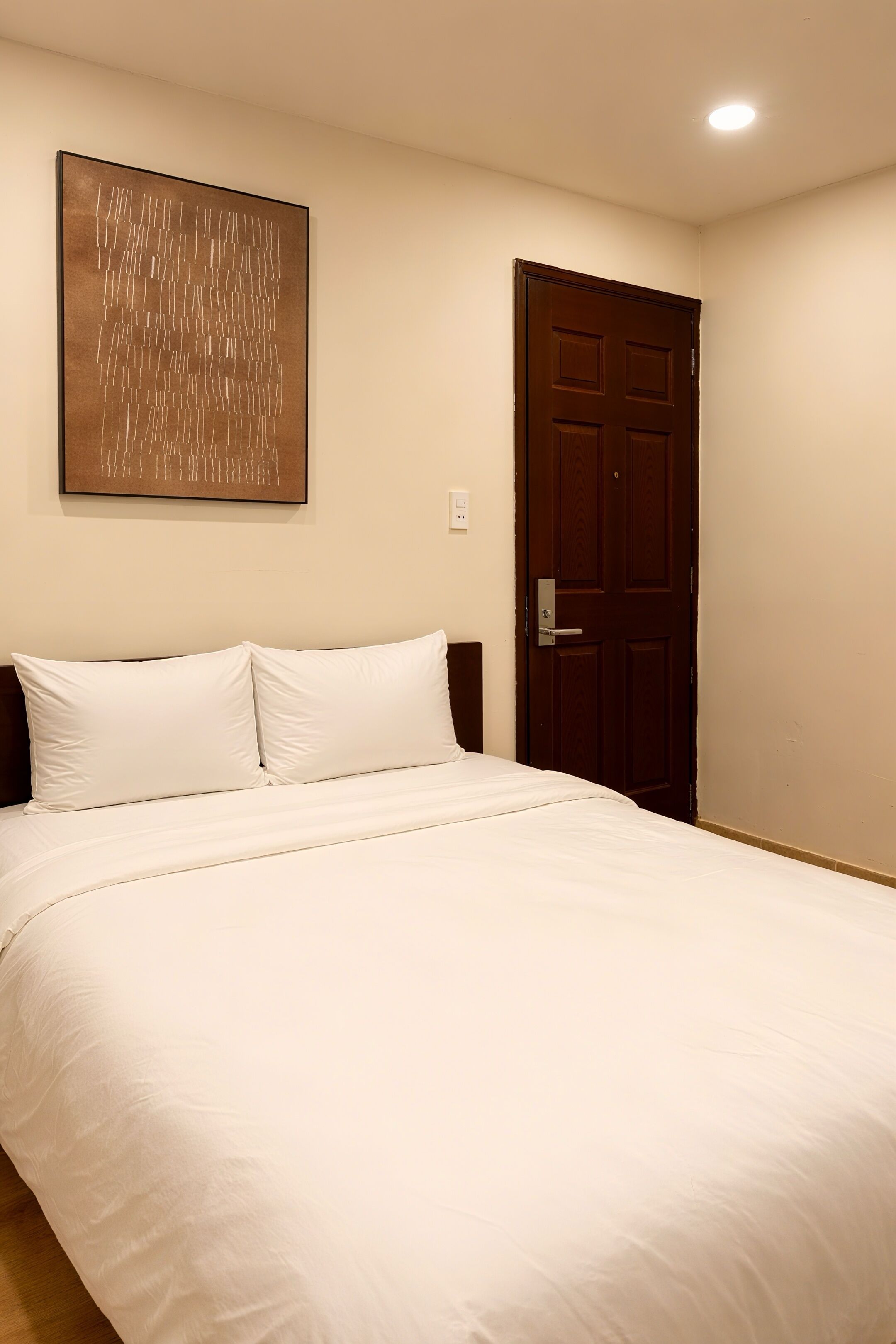 A bedroom with a bed, a door, and a wall-mounted artwork.