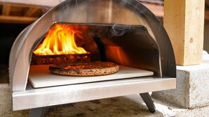 En pizzaovn med en pizza indeni, omgivet af en metalramme.