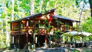 A wooden cabin with a balcony, surrounded by trees. - A private lodge where you can enjoy authentic BBQ surrounded by nature (Tsumagoi)