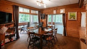 A wooden cabin interior with a dining table, chairs, a television, and a fireplace. - A private lodge where you can enjoy authentic BBQ surrounded by nature (Tsumagoi)
