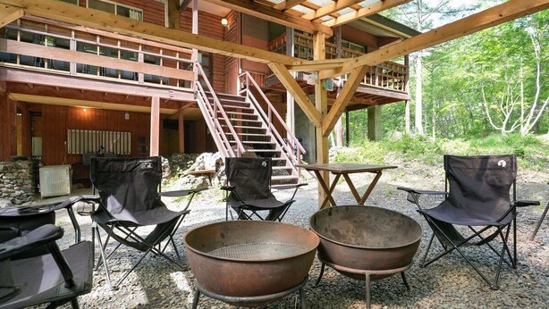 An outdoor patio with a covered seating area, a fireplace, and a staircase leading to an upper level. - A private lodge where you can enjoy authentic BBQ surrounded by nature (Tsumagoi)