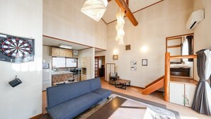 A compact living space with a sofa, a dining area, and a kitchen visible through an open door.