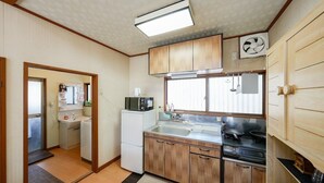 A compact kitchen with wooden cabinets, a microwave, a sink, and a stove.