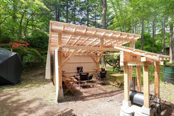 A wooden structure with a roof, seating area, and a table.