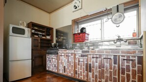 A compact kitchen with a refrigerator, wooden cabinets, a window with a view, and a red basket on the counter.