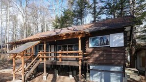 A rustic cabin with a wooden deck and stairs leading to a porch.