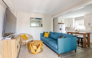 Ein modernes Wohnzimmer mit einem blauen Sofa, einem Holztisch und einem Essbereich mit einem Holztisch und Stühlen.