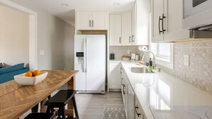 A modern kitchen with white cabinets, a built-in oven, and a stainless steel refrigerator. - 2-bedroom apartment in perfect St. Augustine with hot tub & direct beach access (St. Augustine)