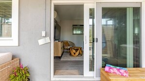 Ein Zimmer mit einer Schiebetür zum Balkon, einem Holztisch und einem Korbkörbchen mit einer Pflanze.