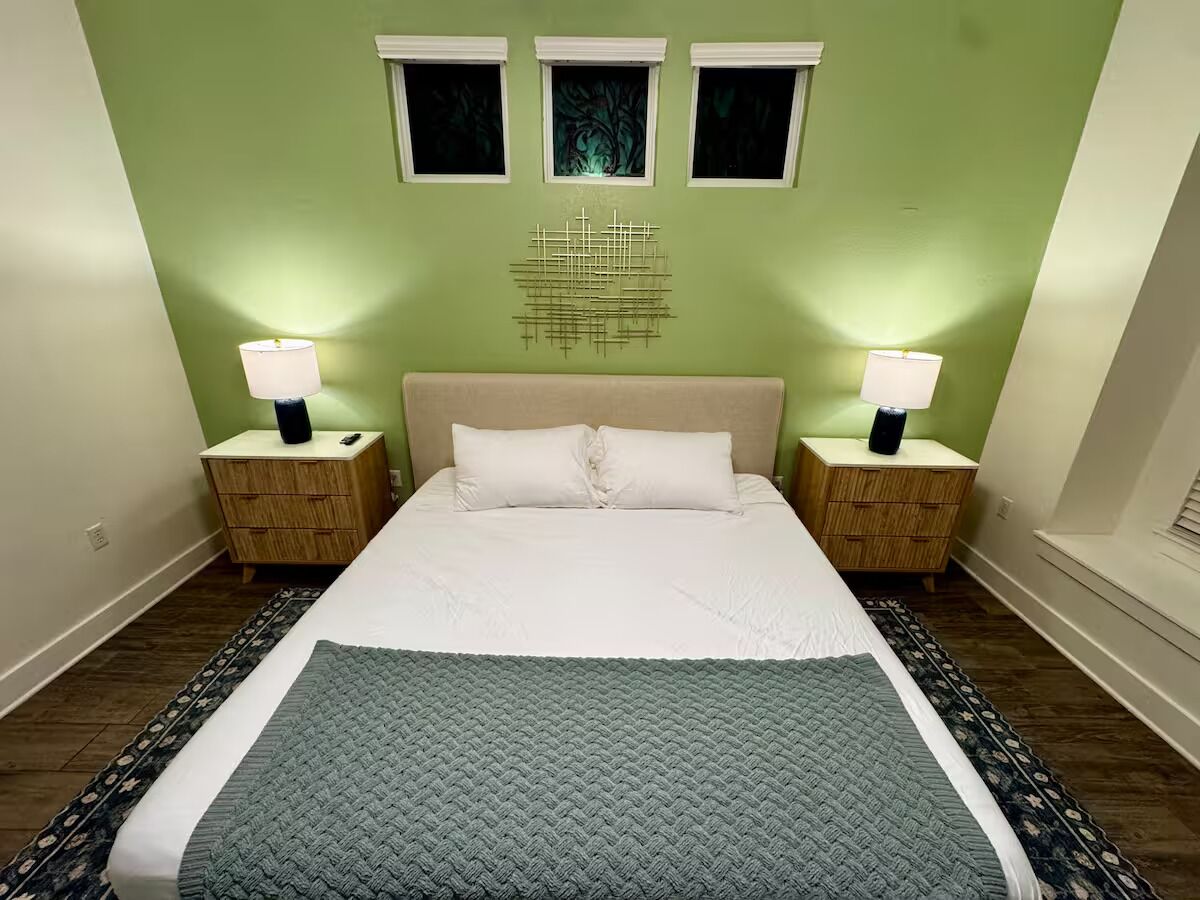 Una camera da letto con un letto grande, due comodini con lampade, un elemento decorativo a parete e un tappeto a motivi.