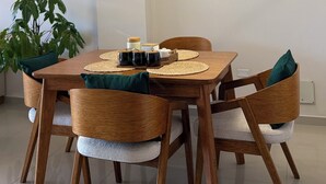 Ein Essbereich mit einem Holztisch, gewobenen Stühlen und einer modernen Pendelleuchte.