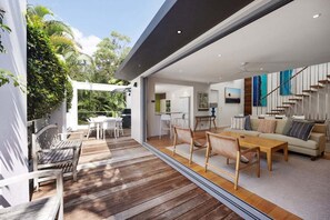 Een modern interieur met een houten terras, een eetgedeelte en een woonkamer met een bank en een trap.