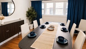 Un comedor con una mesa de madera oscura, sillas blancas y platos azules.