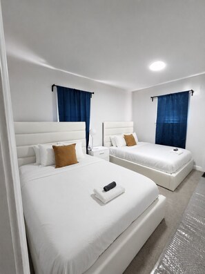 A hotel room with two beds, white bedding, and blue curtains. - Dogs Welcome!  Fun, Stylish Detroit Tudor w/ Fenced Yard! (Detroit)