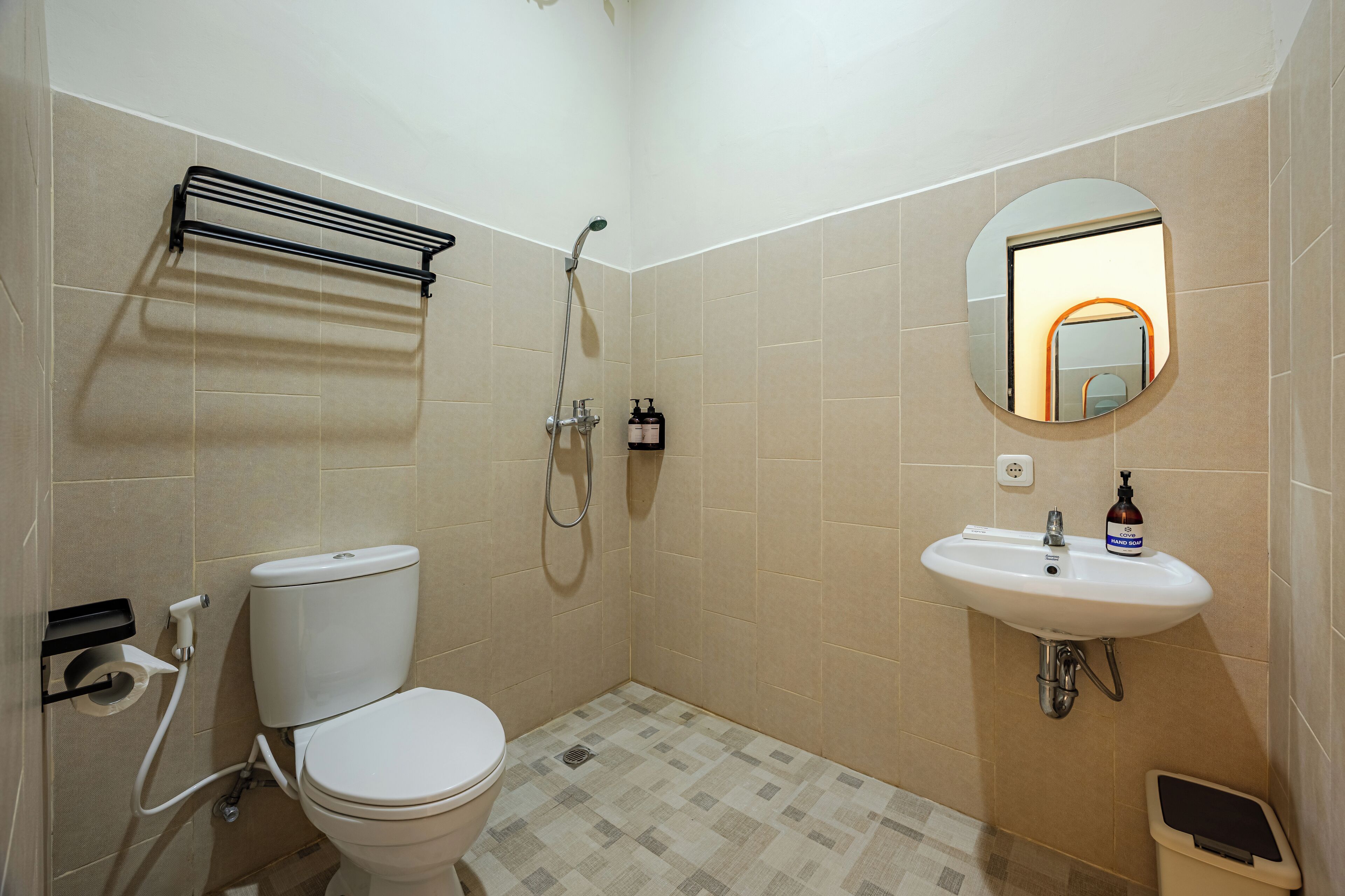 A bathroom with a toilet, shower, sink, and a mirror.