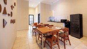 A modern kitchen with a black refrigerator, wooden dining table, and chairs. - Cove Chara (Jimbaran)