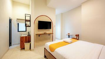 Una habitación de hotel con una cama, un televisor en la pared, una mesita pequeña y una silla.