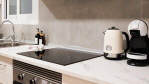 Ett modernt kök med en svart induktionshäll, en kaffebryggare och en vattenkokare.