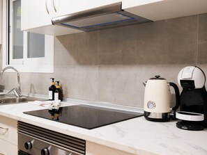 A modern kitchen with a black induction cooktop, a coffee maker, and a kettle. - Apartamento Plaza de España (Palma de Mallorca)