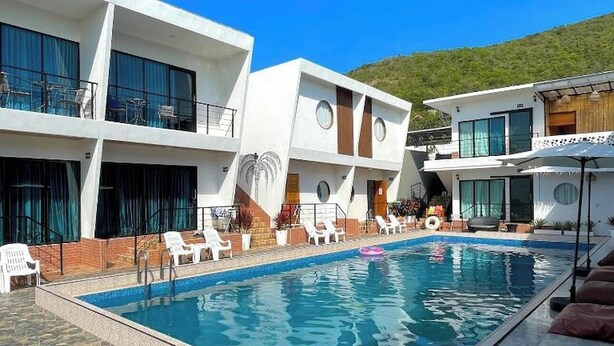 A modern hotel with a swimming pool, multiple balconies, and a view of a hill. - Lastsearesort (Koh Lan)