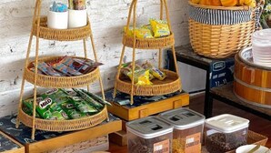 A breakfast buffet setup with wicker baskets, food containers, and mugs. - Lastsearesort (Koh Lan)