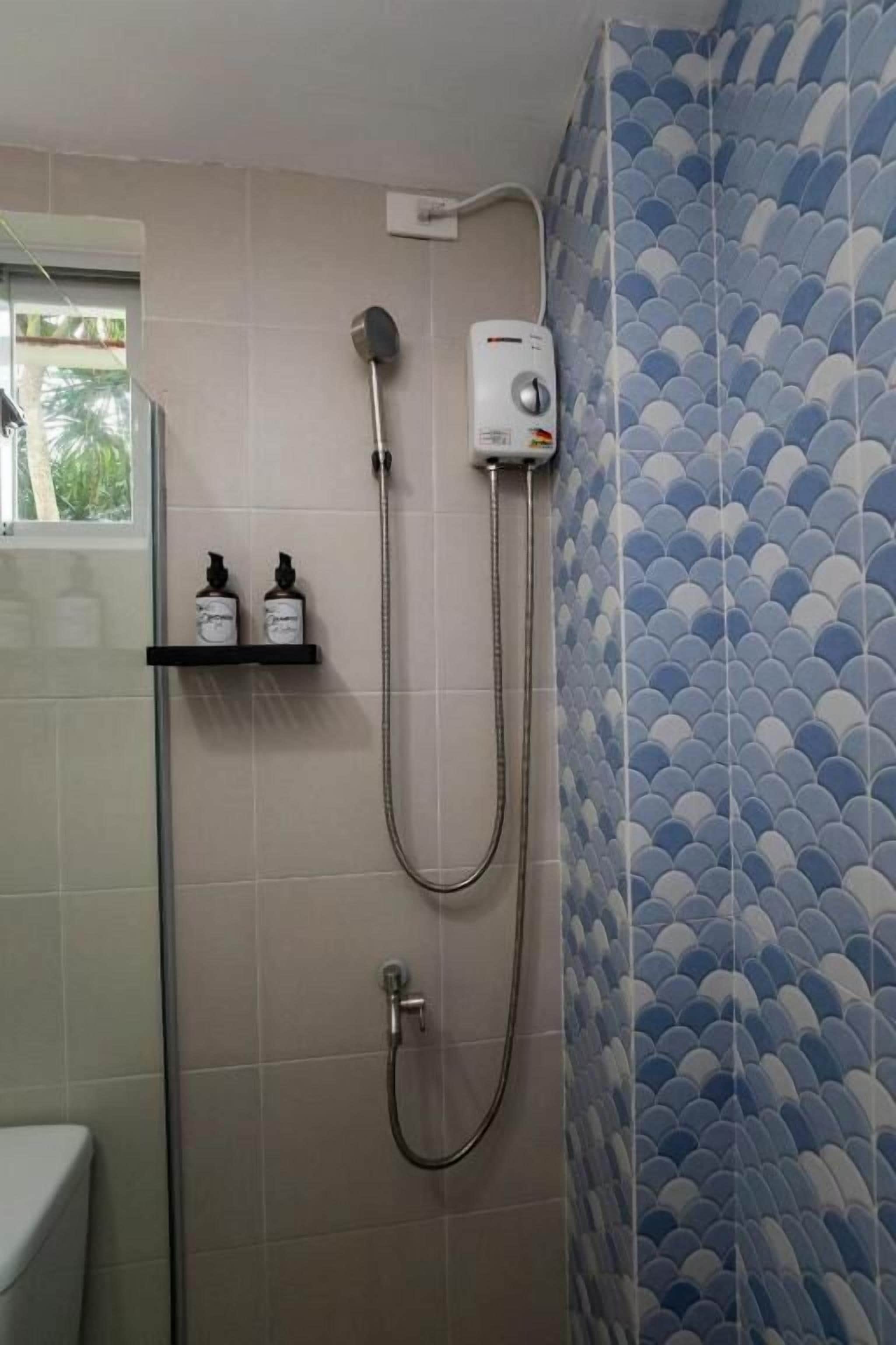 A bathroom with a shower, a toilet, and a shelf with toiletries.