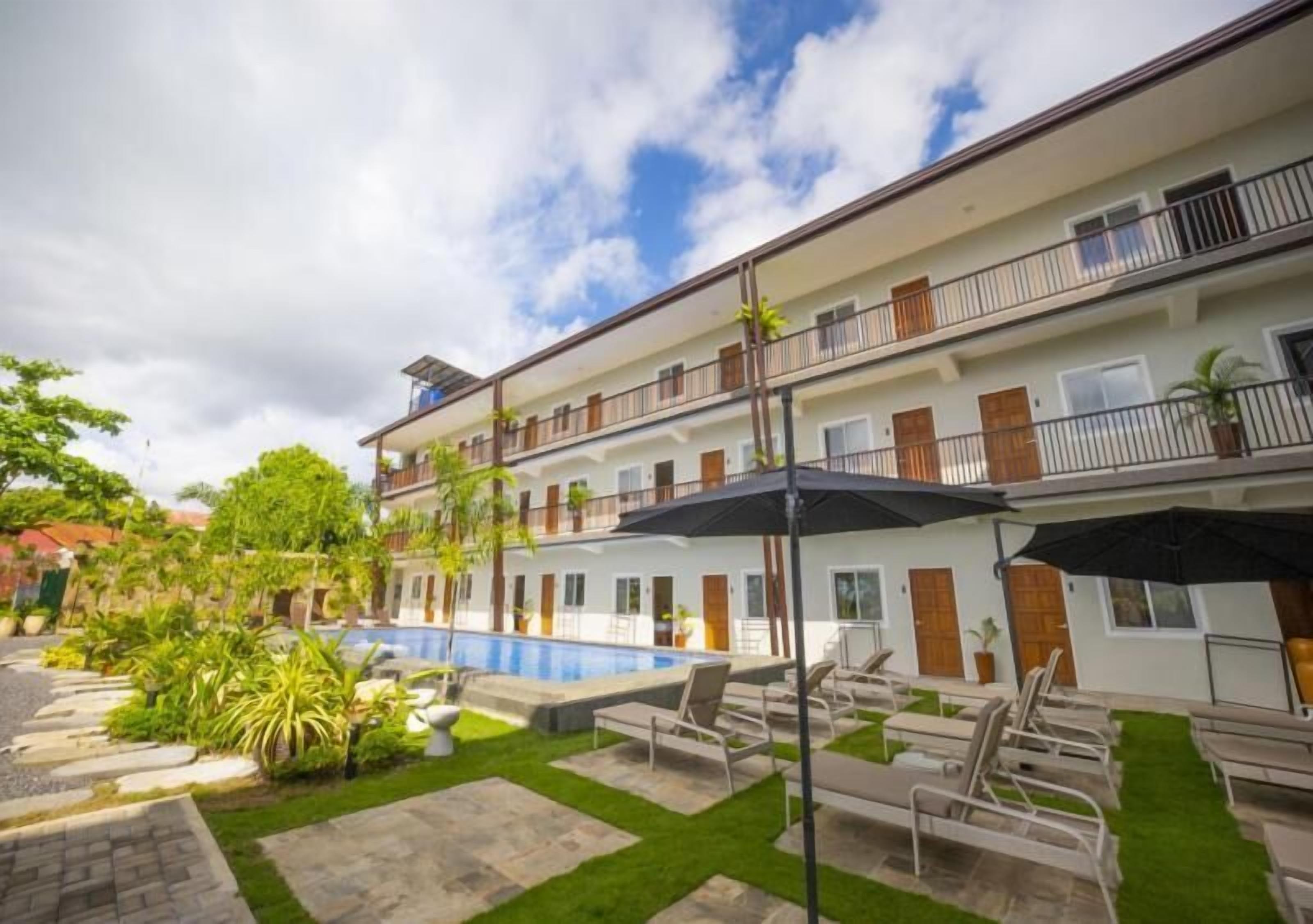 Un hotel de varios pisos con piscina, zona de estar al aire libre y jardín.