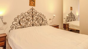 A neatly made bed with a decorative headboard, bedside tables with lamps, and a large mirror on the wall.