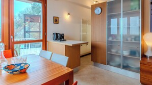 A modern kitchen with a wooden countertop, a coffee machine, and a clock on the wall.