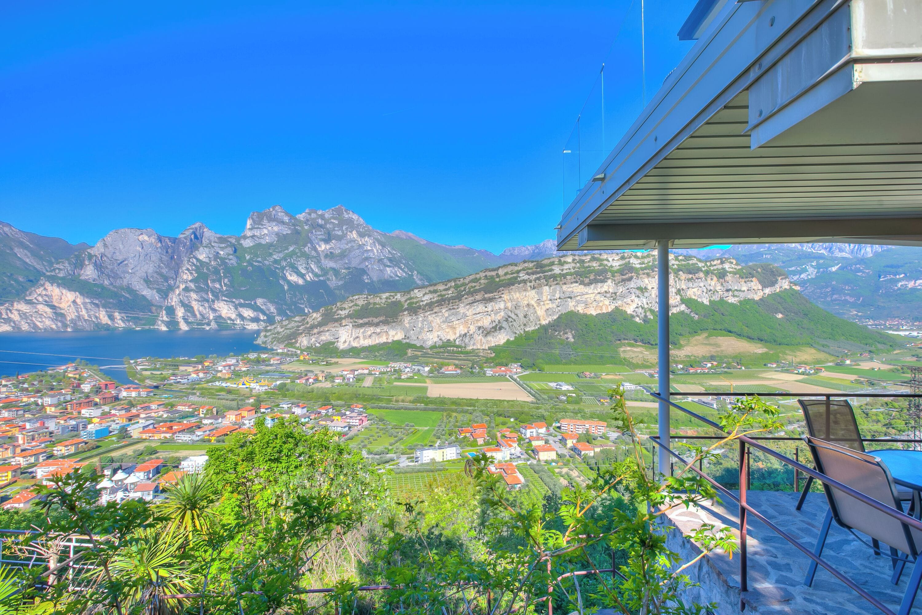 A balcony with a view of a coastal town, mountains, and a body of water.