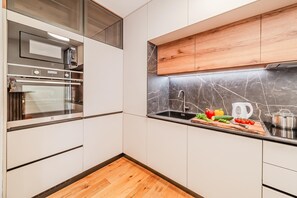 A modern kitchen with a built-in oven, a stainless steel sink, and a wooden countertop. - Aurora Park Near Bundek (Zagreb)