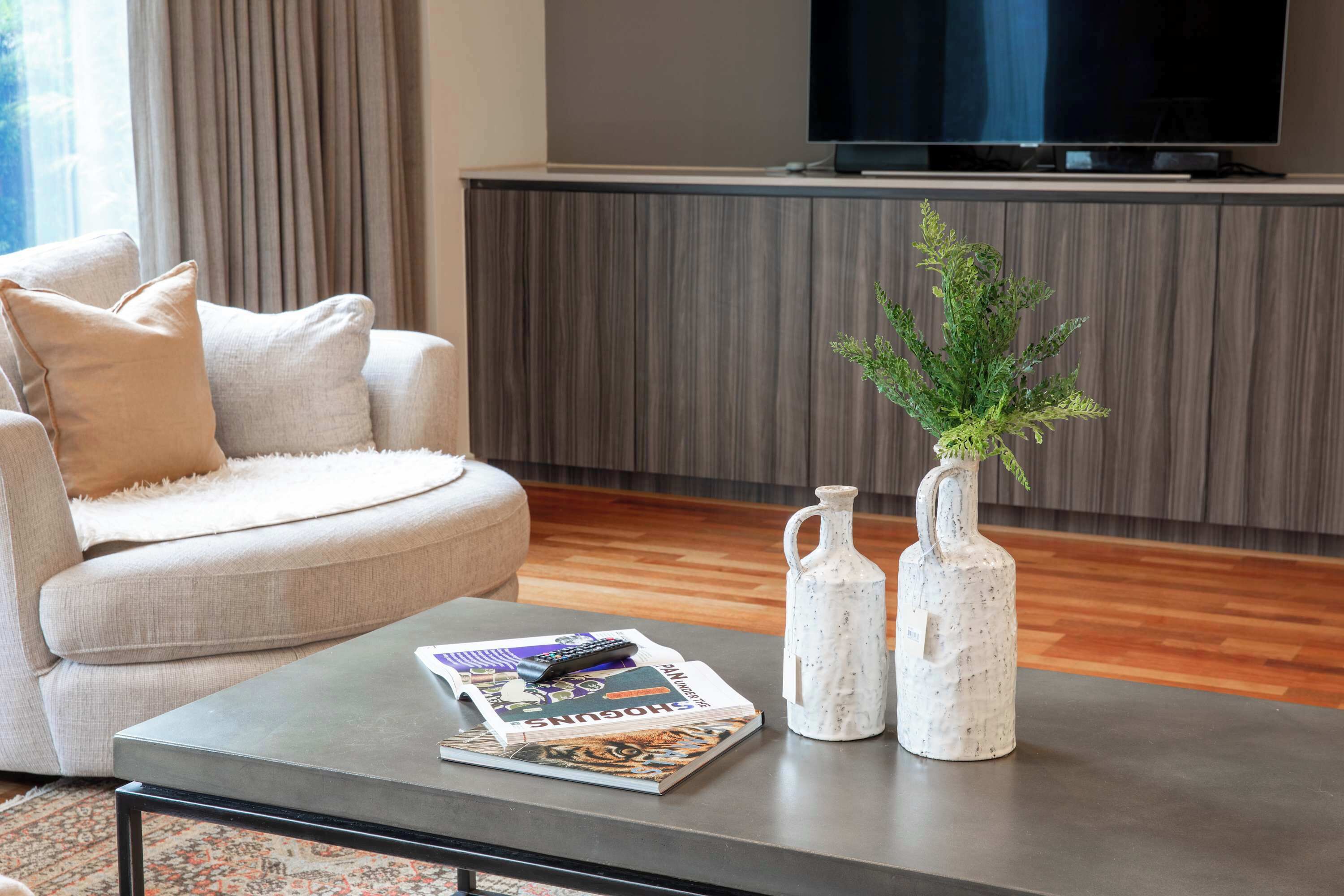 Sala de estar com sofá, mesa de centro e dois vasos com plantas.