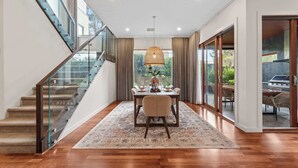 Un intérieur moderne avec un escalier, un coin repas et de grandes fenêtres.