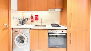 Ett kompakt kök med träskåp, en inbyggd tvättmaskin, en spis och en diskmaskin.