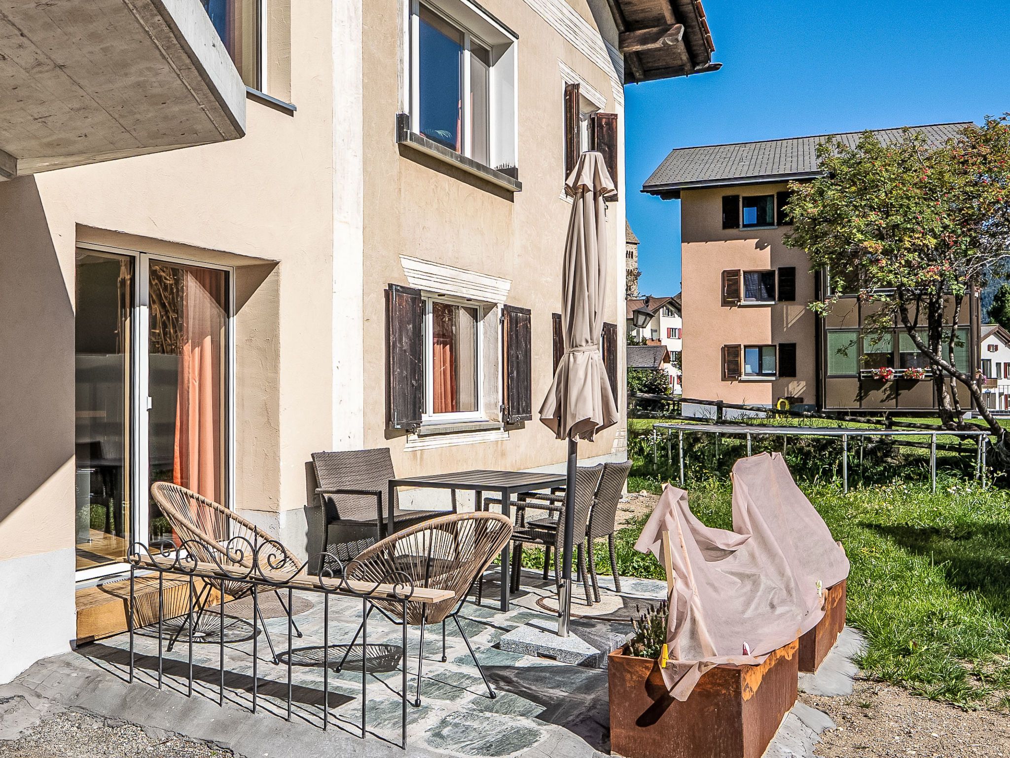 Ein Gebäude mit einer Terrasse, die Gartenmöbel und einen überdachten Tisch bietet.