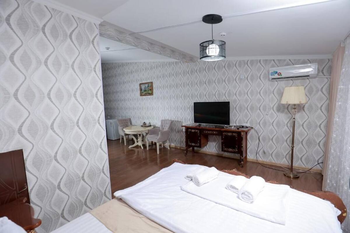 A hotel room with a bed, a desk, a chair, a television, and an air conditioning unit.