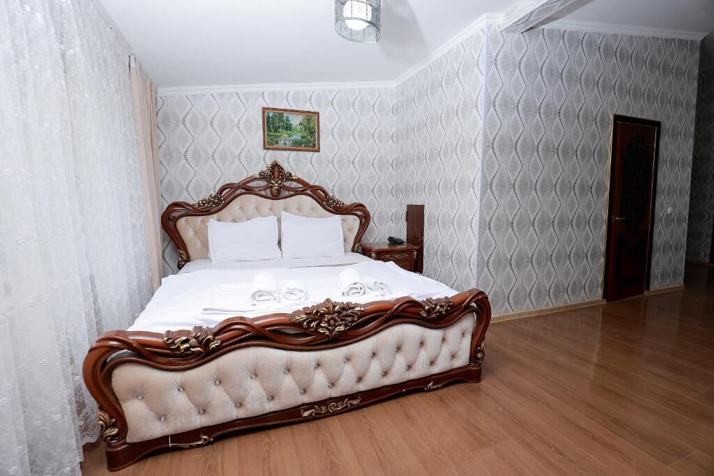 Un dormitorio espacioso con una cama grande, un cabecero de madera y un cuadro en la pared.