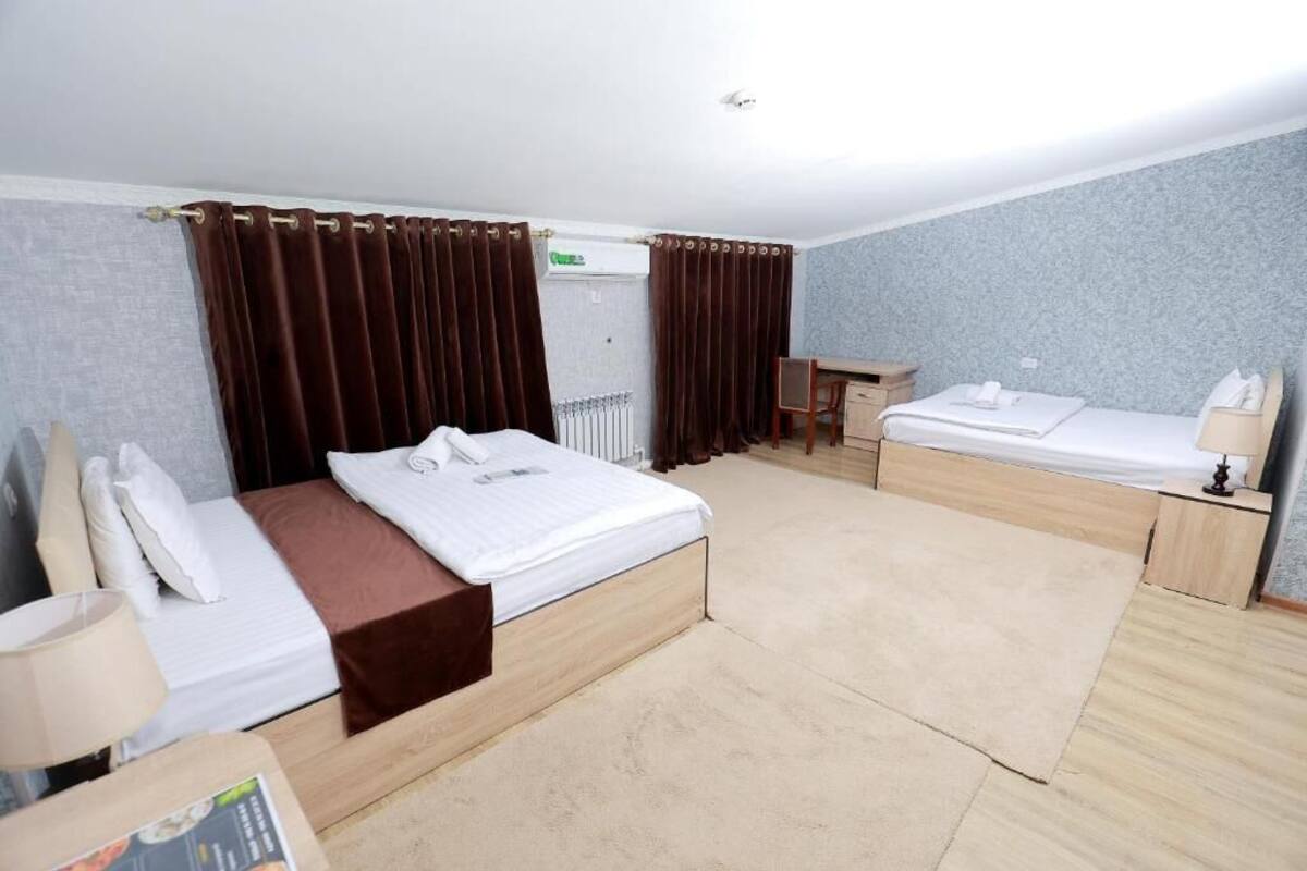 A hotel room with a large bed, a smaller bed, a desk, and a chair.