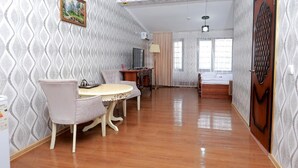 A room with a dining table and chairs, a TV, and a bed.