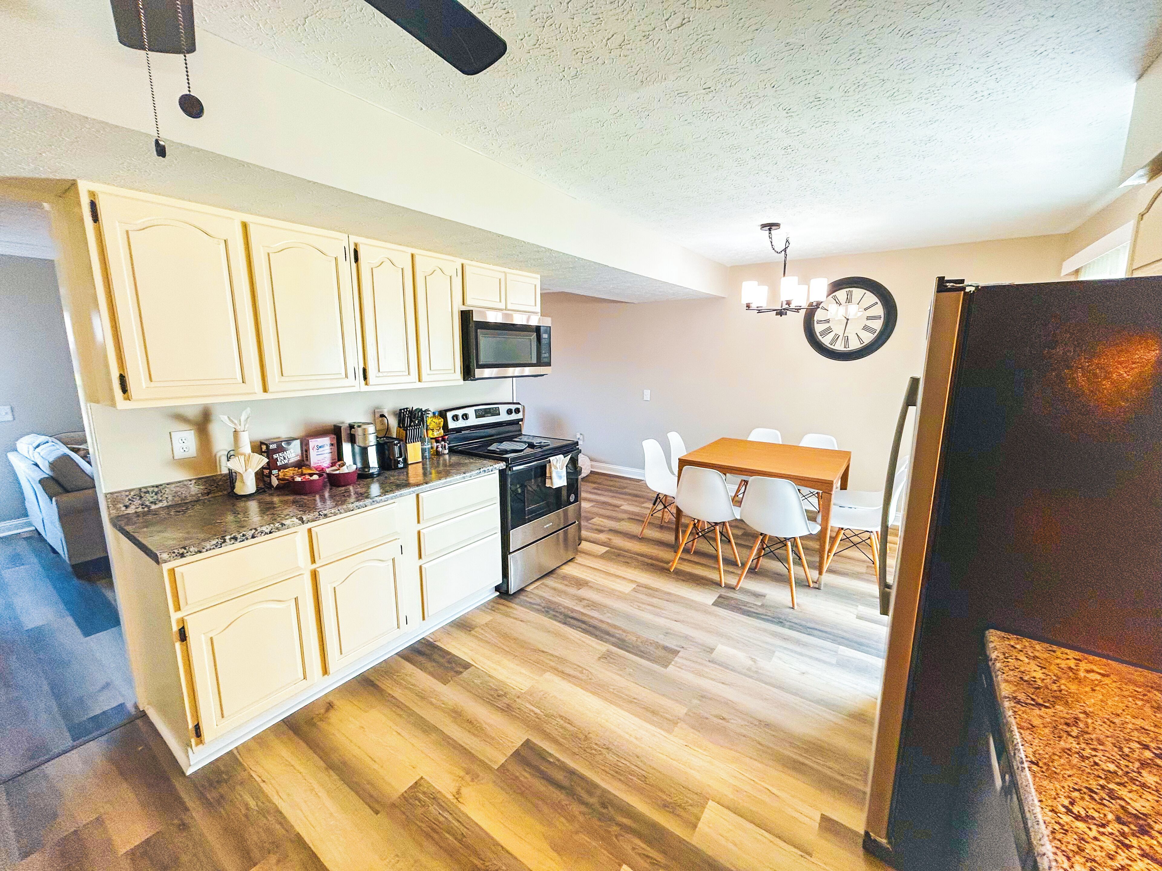 A kitchen with wooden flooring, a dining area with a table and chairs, and a refrigerator.