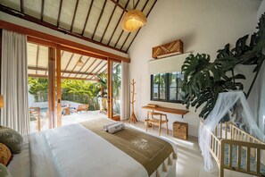 Un dormitorio con cama, escritorio, silla, una planta grande y vistas al exterior.