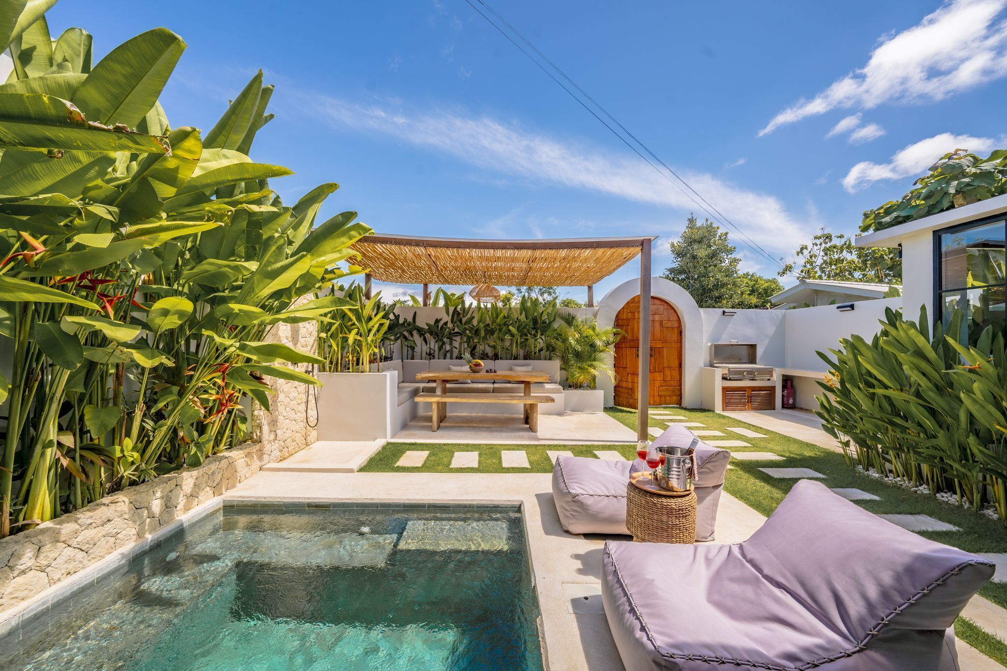 A pool area with a seating arrangement, a pergola, and a barbecue area.