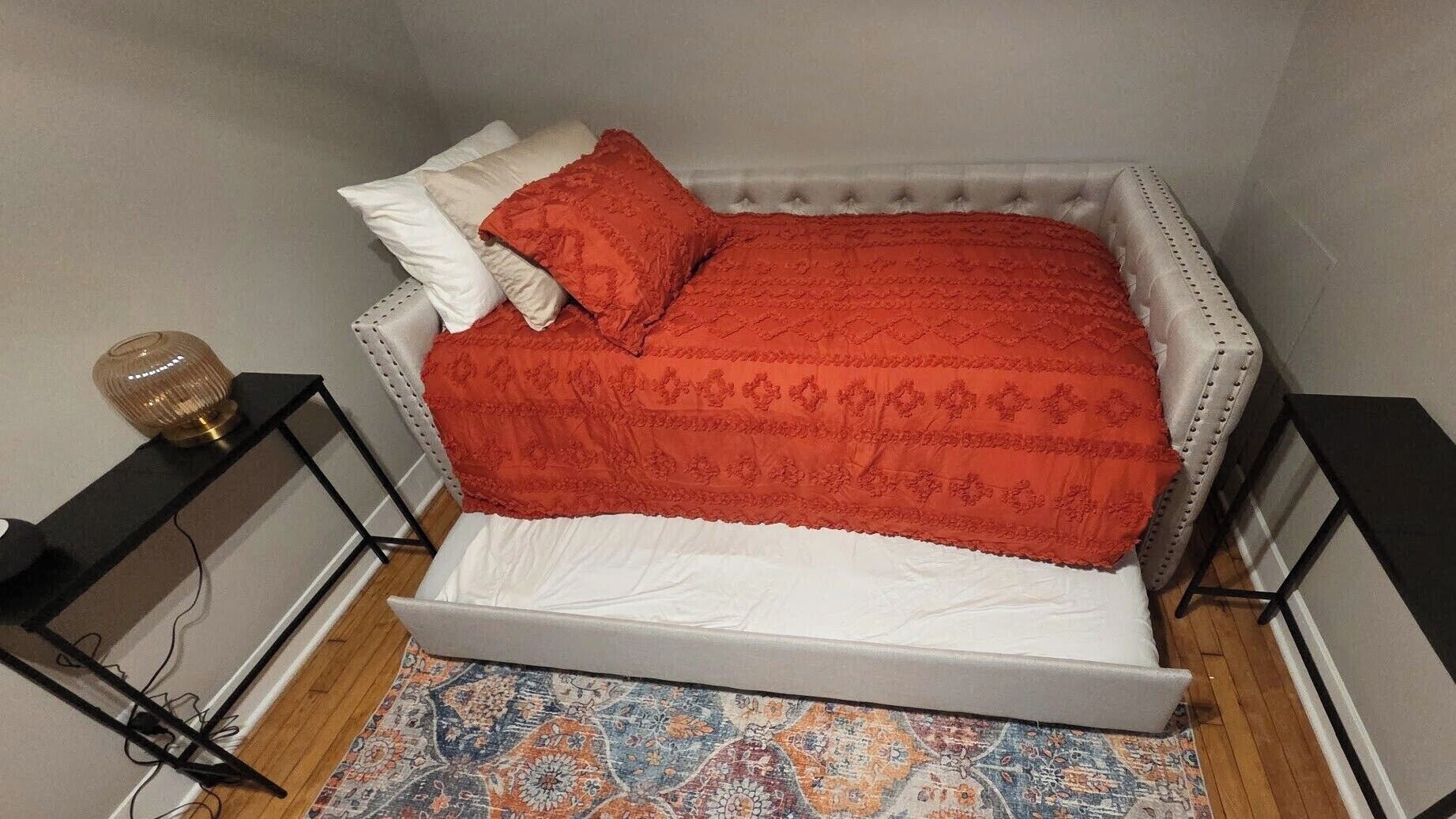Una camera da letto con un letto, un tappeto decorato e due comodini con lampade.
