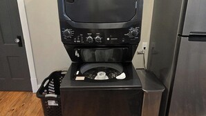 Une cuisine compacte équipée d’un four encastré, d’un réfrigérateur et d’un téléviseur fixé au-dessus du four.