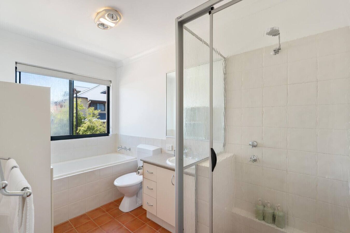 A modern bathroom with a shower, toilet, and sink.