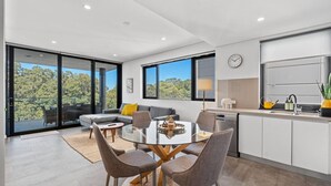 A modern kitchen with a dining area, large windows, and a view of the outdoors. - South Perth Sky - Foreshore Escape (Perth)