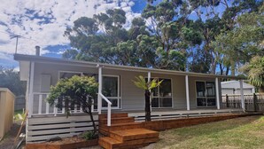 A single-story house with a porch, a small garden area, and a view of surrounding trees. - Island Getaway on Bay - Pet friendly - Wifi - Winter special 4th night free (Cowes)