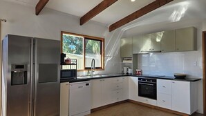 A modern kitchen with stainless steel appliances, white cabinetry, and exposed wooden beams. - Island Getaway on Bay - Pet friendly - Wifi - Winter special 4th night free (Cowes)