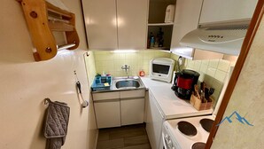 A compact kitchen with a sink, microwave, coffee maker, and stove. - Le Pradet A 781 - Mont Dore 4 Pers (Mont-Dore)