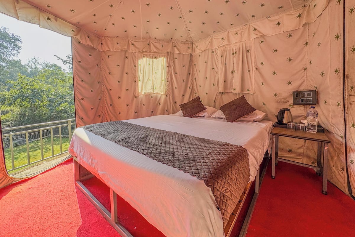 A tent-style room with a bed, pillows, a nightstand, and a window.